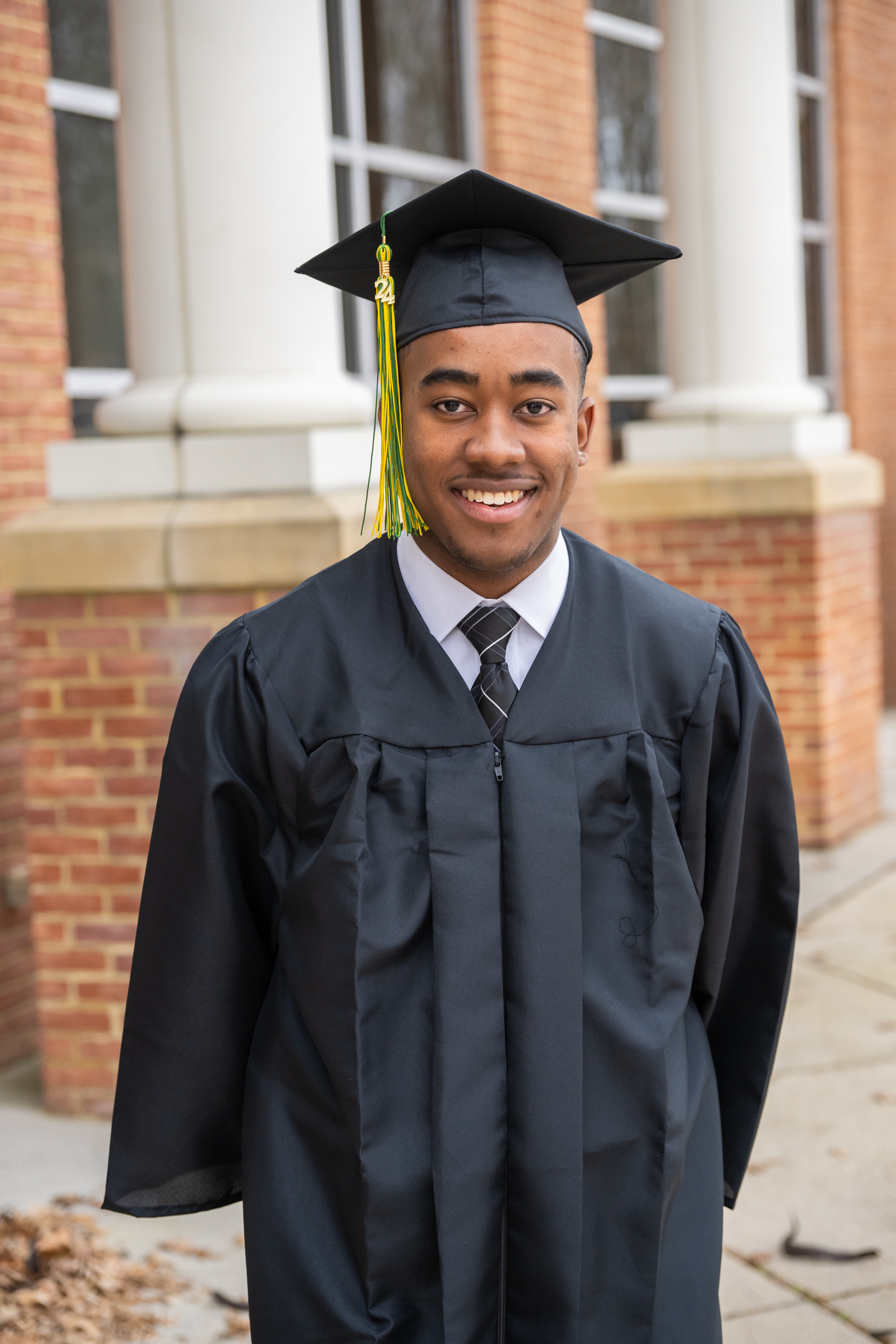 Young man smiles in his cap and gown