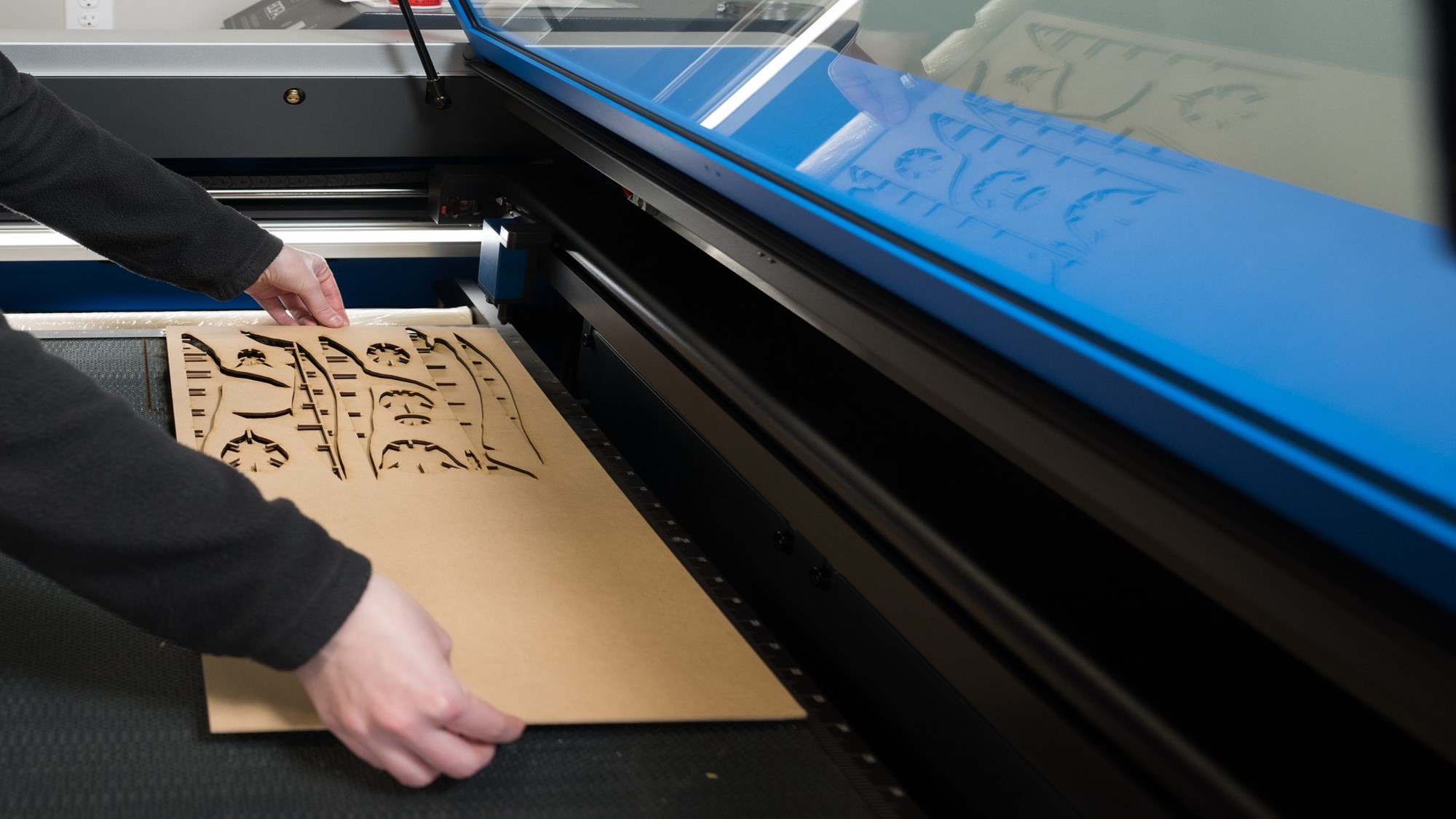Person removes lasercut pieces from a machine