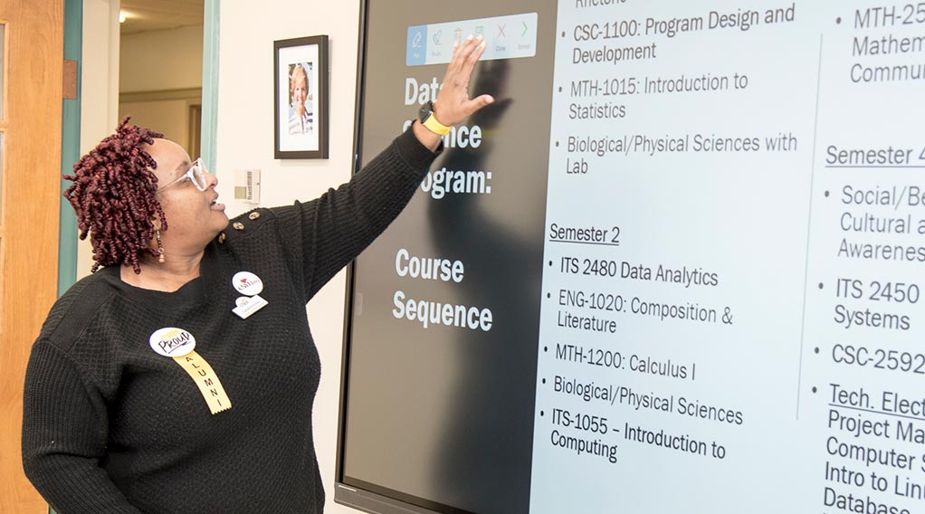 Instructor lectures and motions to a screen