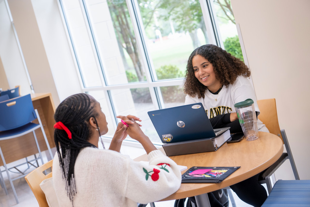 Students sitting with laptop and books