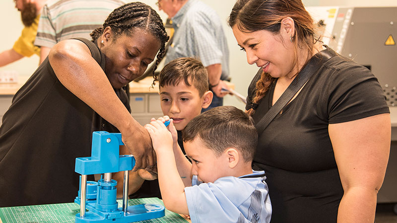 Kids work with an employee to operate a machine