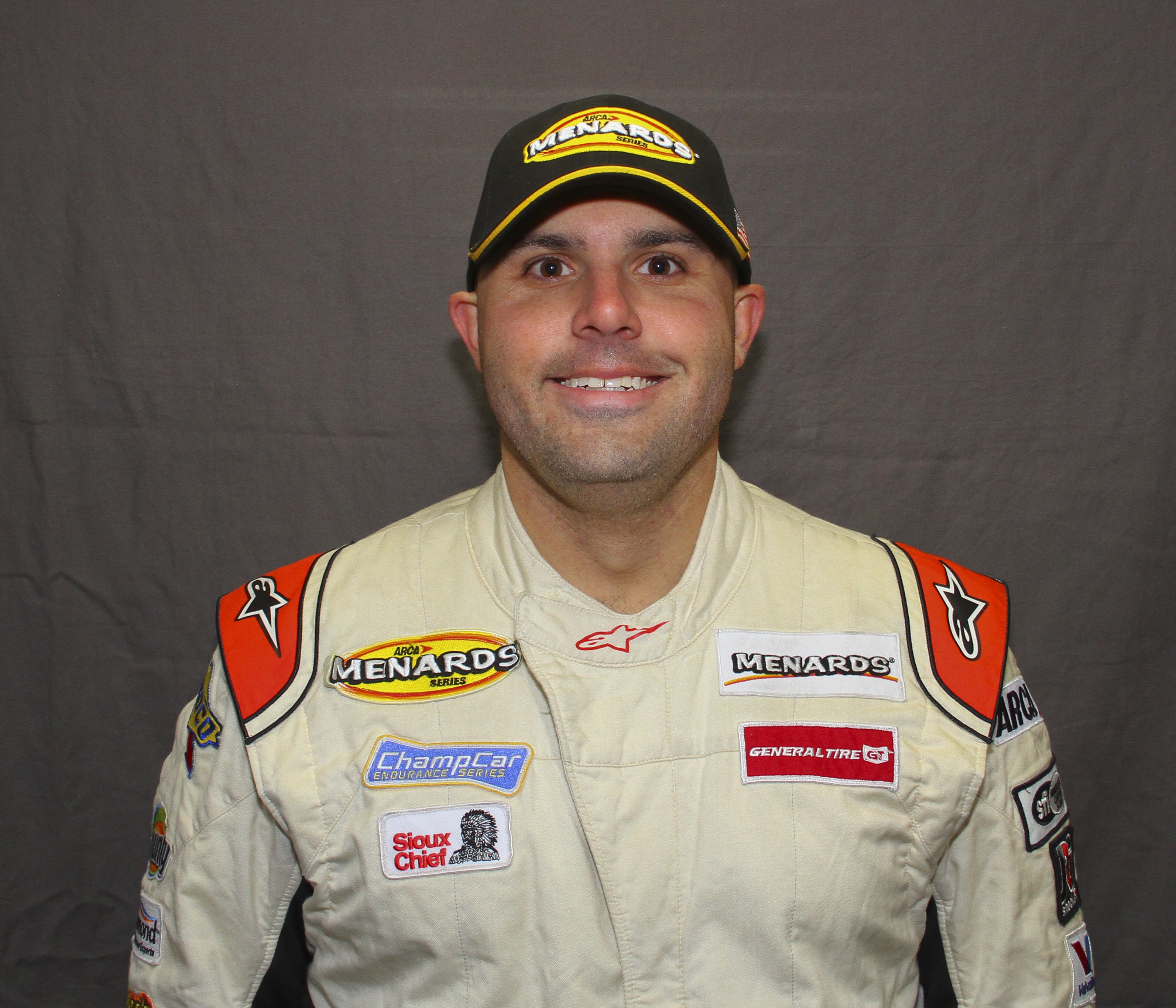 Headshot of CSM graduate Kyle Lockrow, dressed in a racing jumpsuit and smiling at the camera