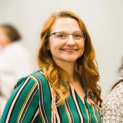 Headshot of CSM graduate Wendy Bollino. She has glasses and red hair and is smiling at the camera.