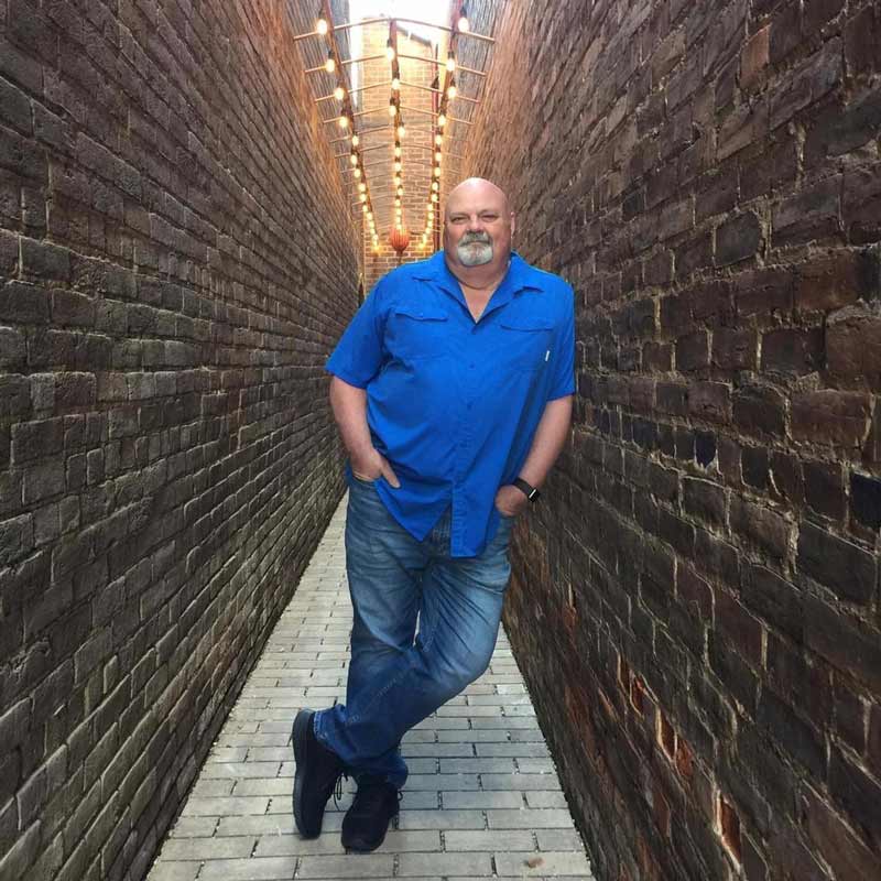 photo of man leaning on brick wall