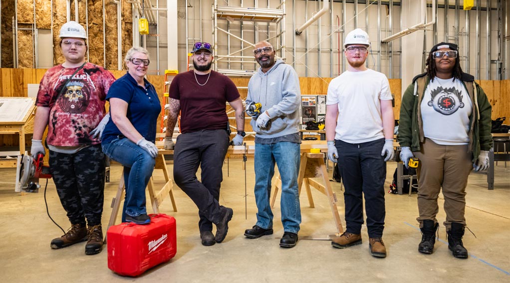 Construction trades students in hard hats in a workshop space