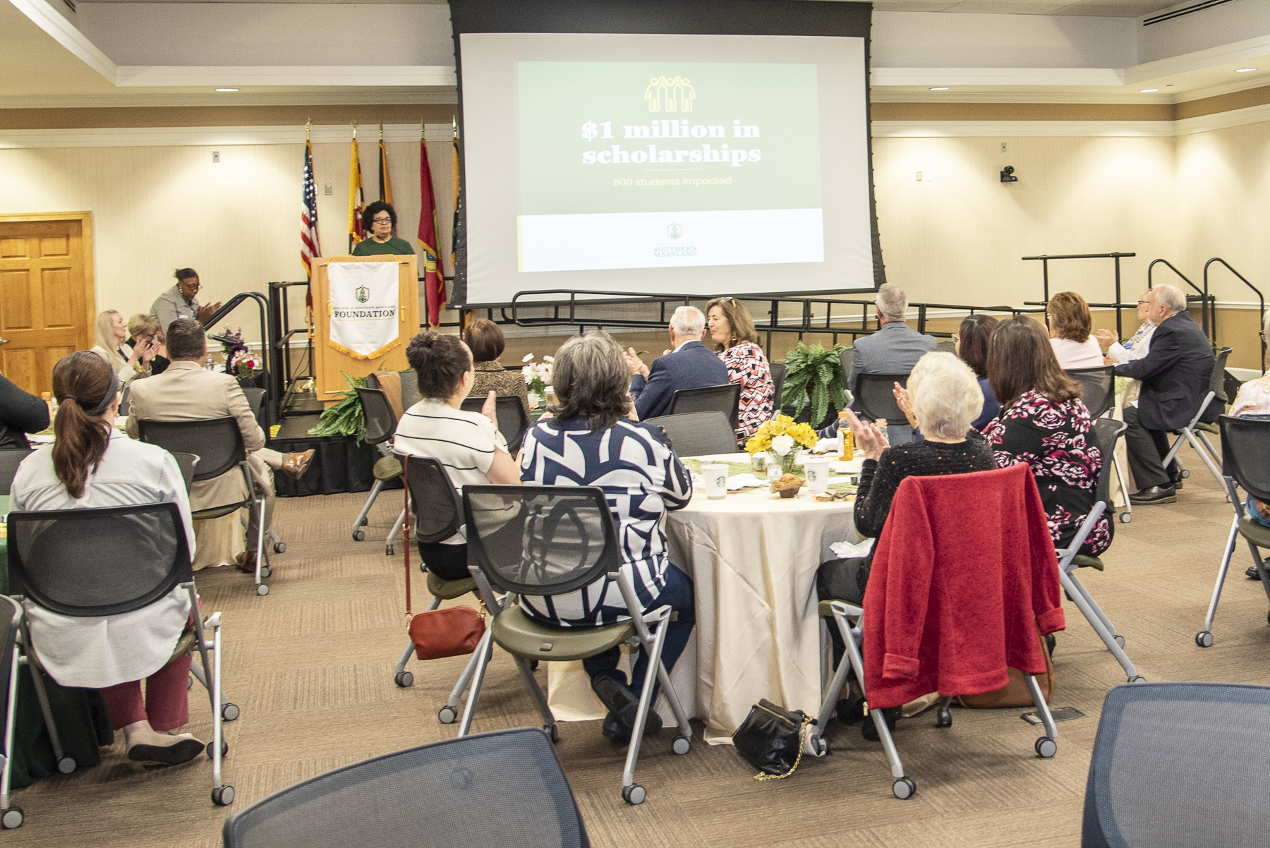 CSM President speaks at a podium in front of tables of donors