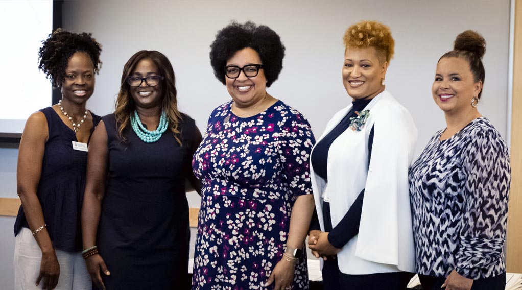 A group of five women posing together, showcasing a diverse range of styles and expressions in a professional setting.