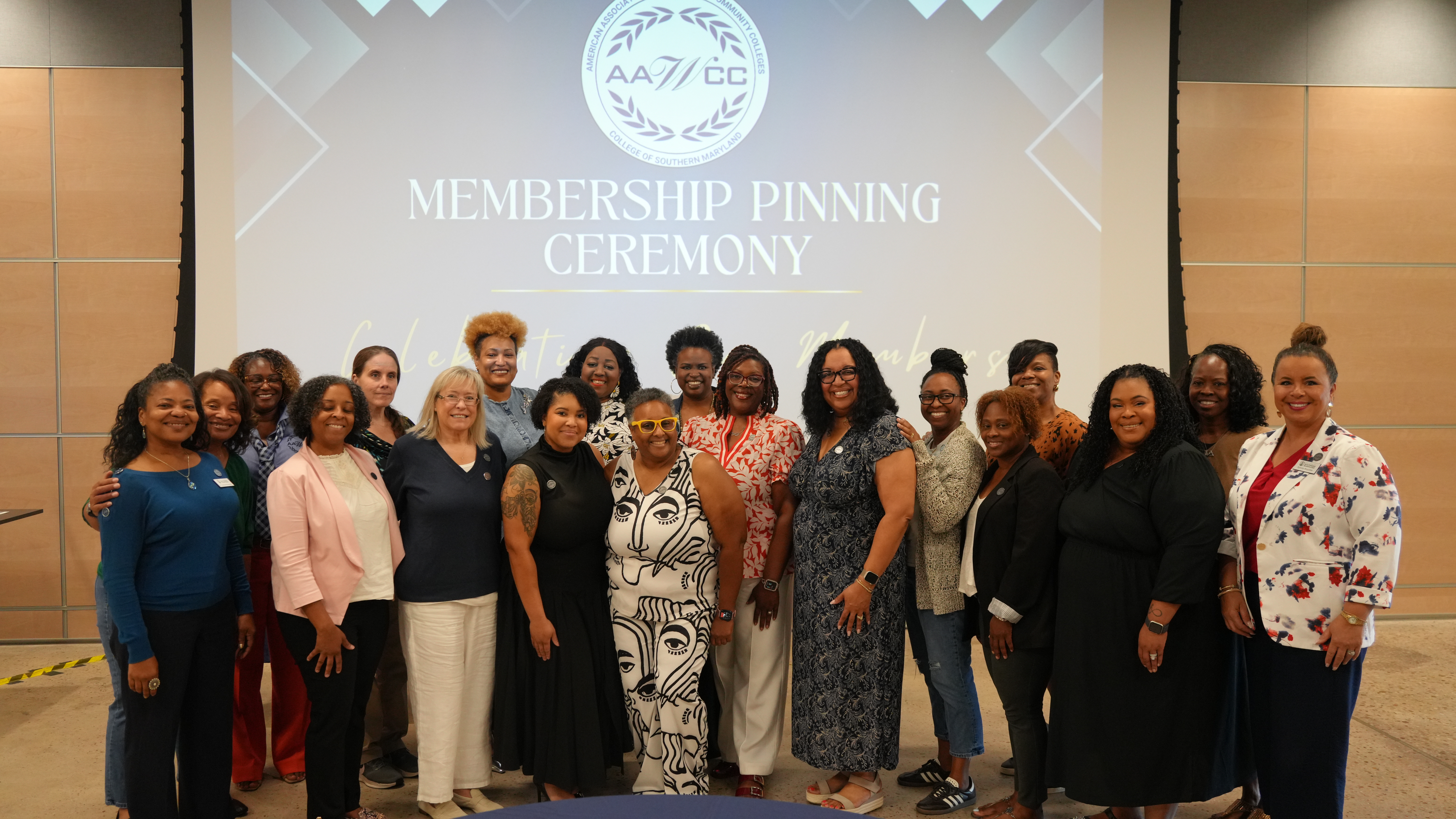 AAWCC chapter members stand together under Membership Pinning Ceremony sign and AAWCC logo