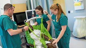 Three nursing students assisting person in a wheelchair