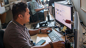 Man sitting at a computer workstation with hands on keyboard