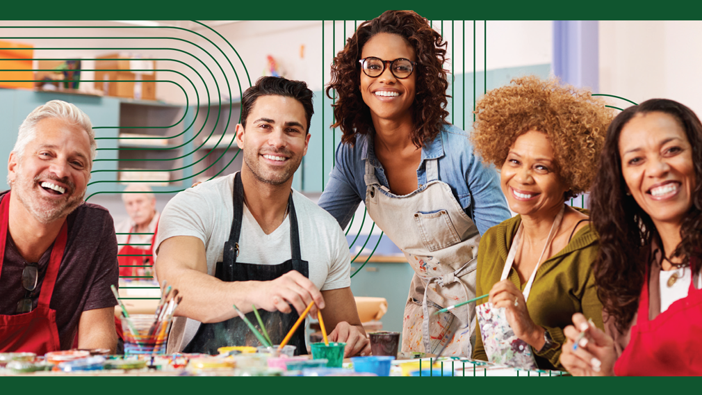 group of people in kitchen with aprons