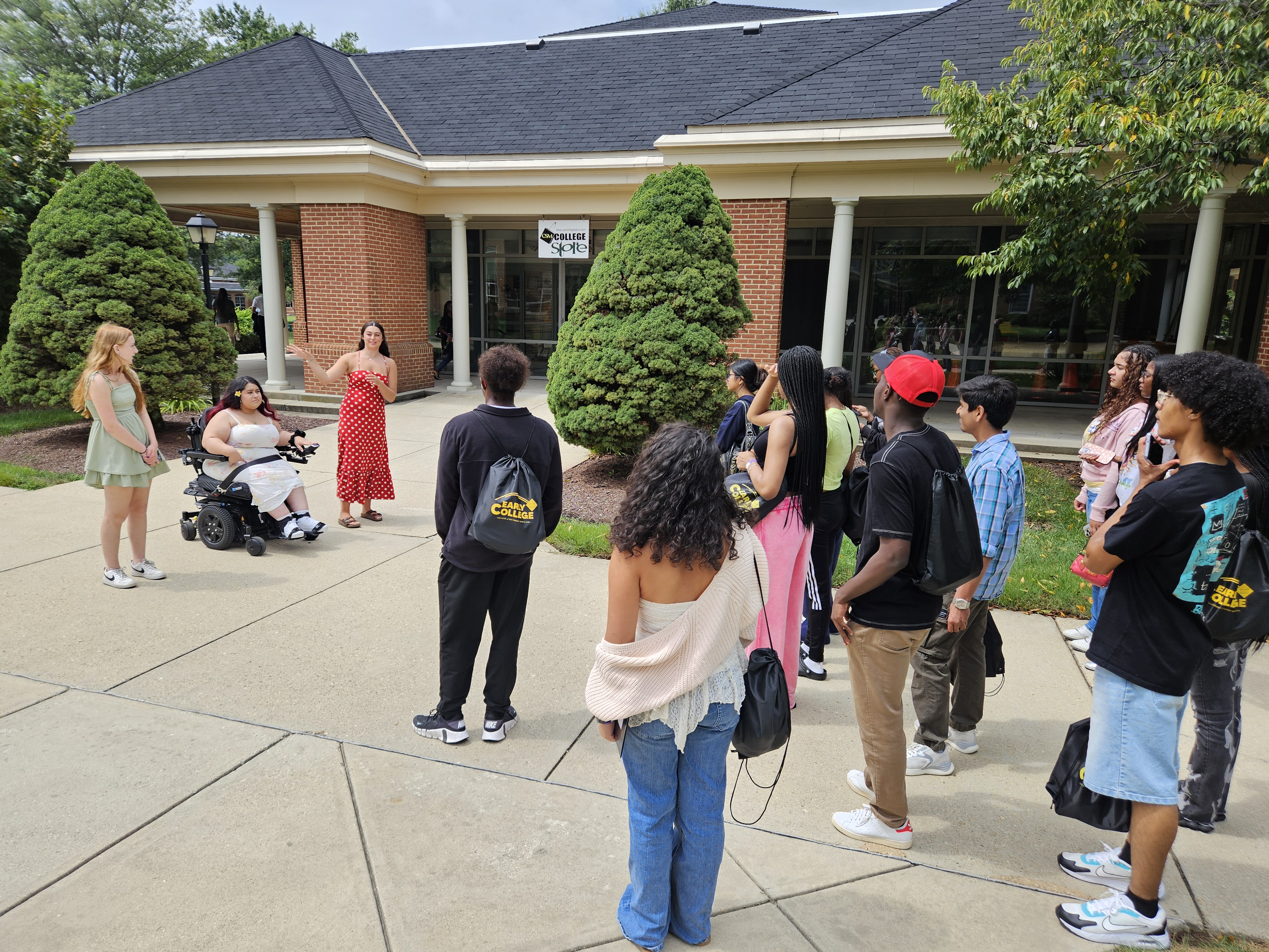Three second-year Early College students stand facing large group of new students giving a tour of campus