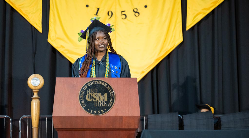 Student smiles while giving speech at the podium during graduation