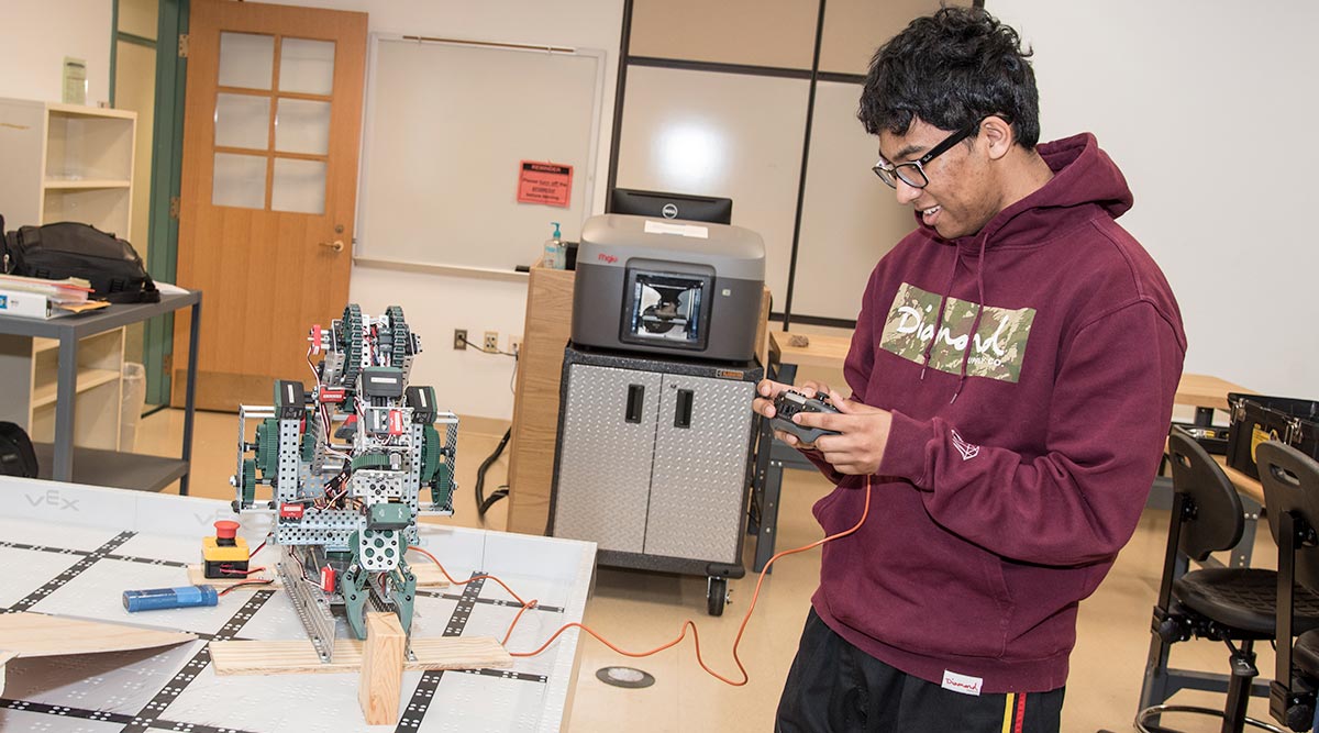 male student holding remote for robotic movement