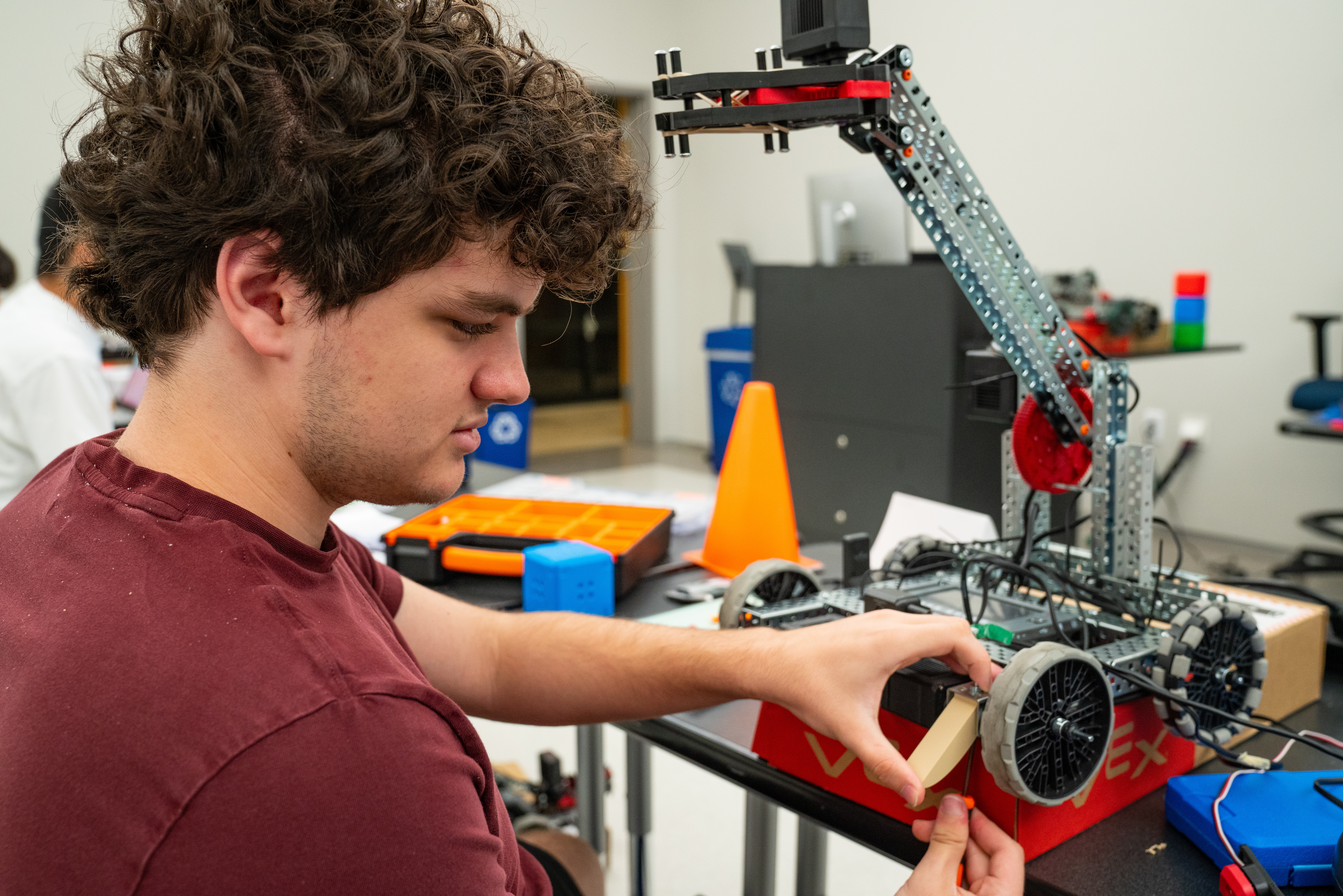 Student works on attaching a piece to a robot atop table 