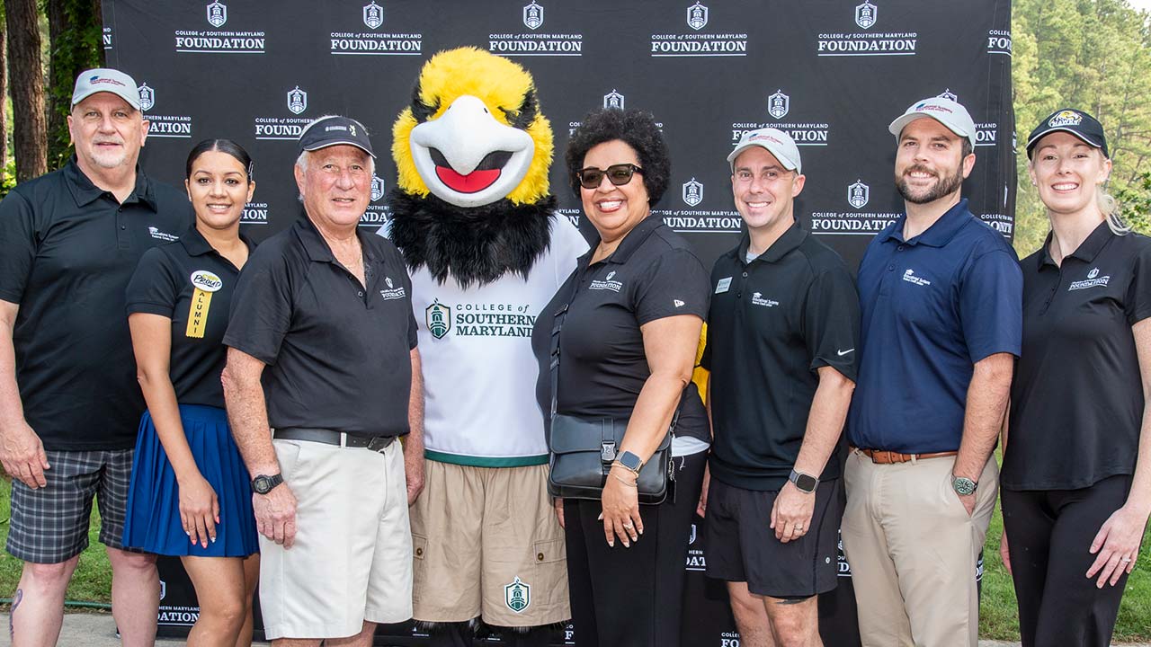 Group photo of individuals posing with a mascot at a College of Southern Maryland event, displaying camaraderie and school spirit.