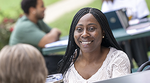 Female talking to someone on a bench in a college setting