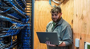 man with laptop in network wiring closet