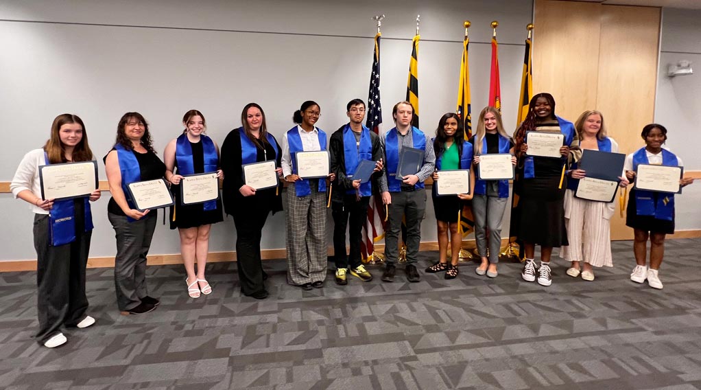 Award winners stand in a row holding their certificates