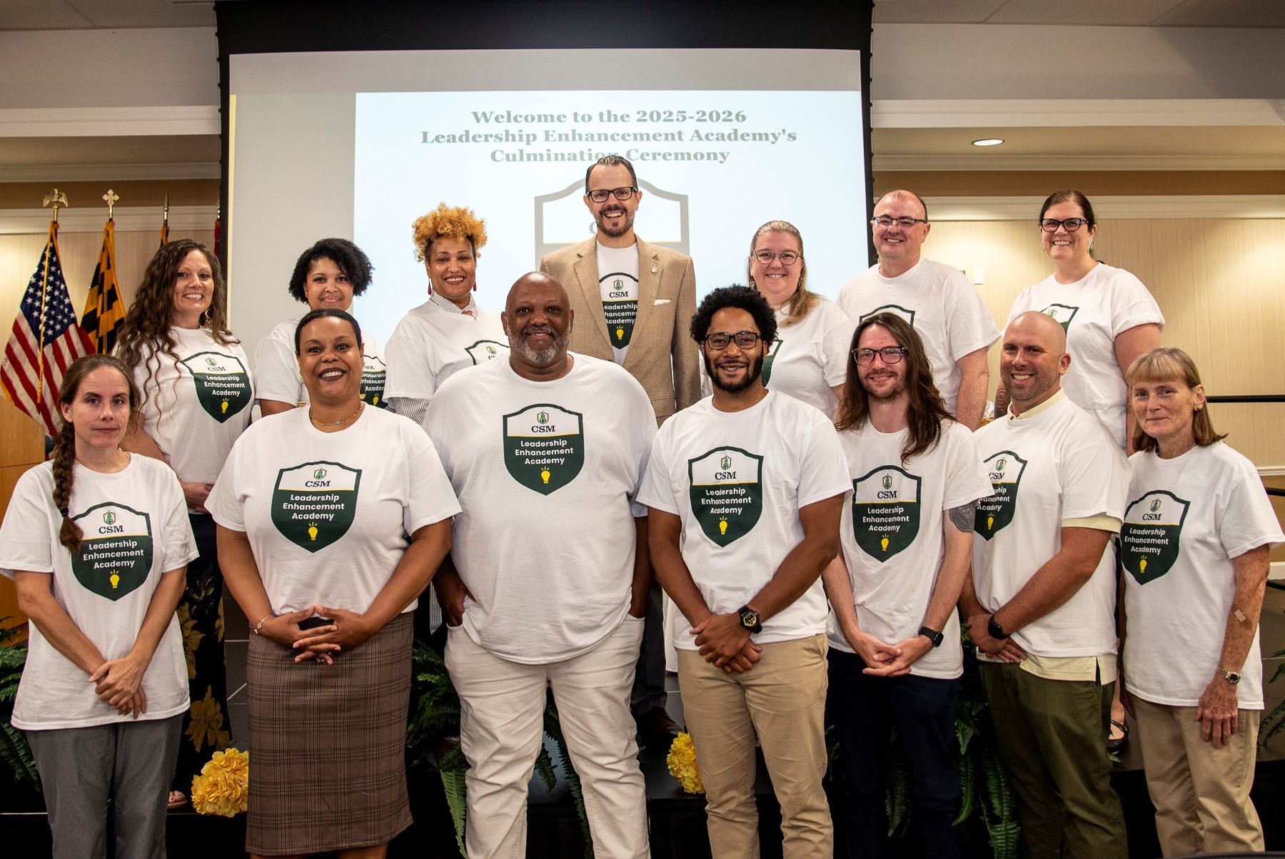 Leadership Enhancement Academy cohort stands on podium during culmination ceremony