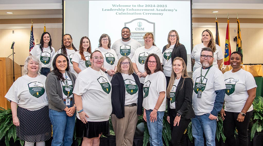 Group of 20 people at a ceremony wearing Leadership Academy t-shirts