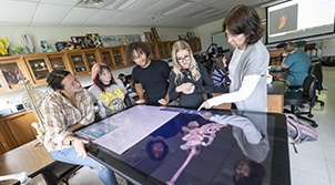 group of people in kitchen with aprons