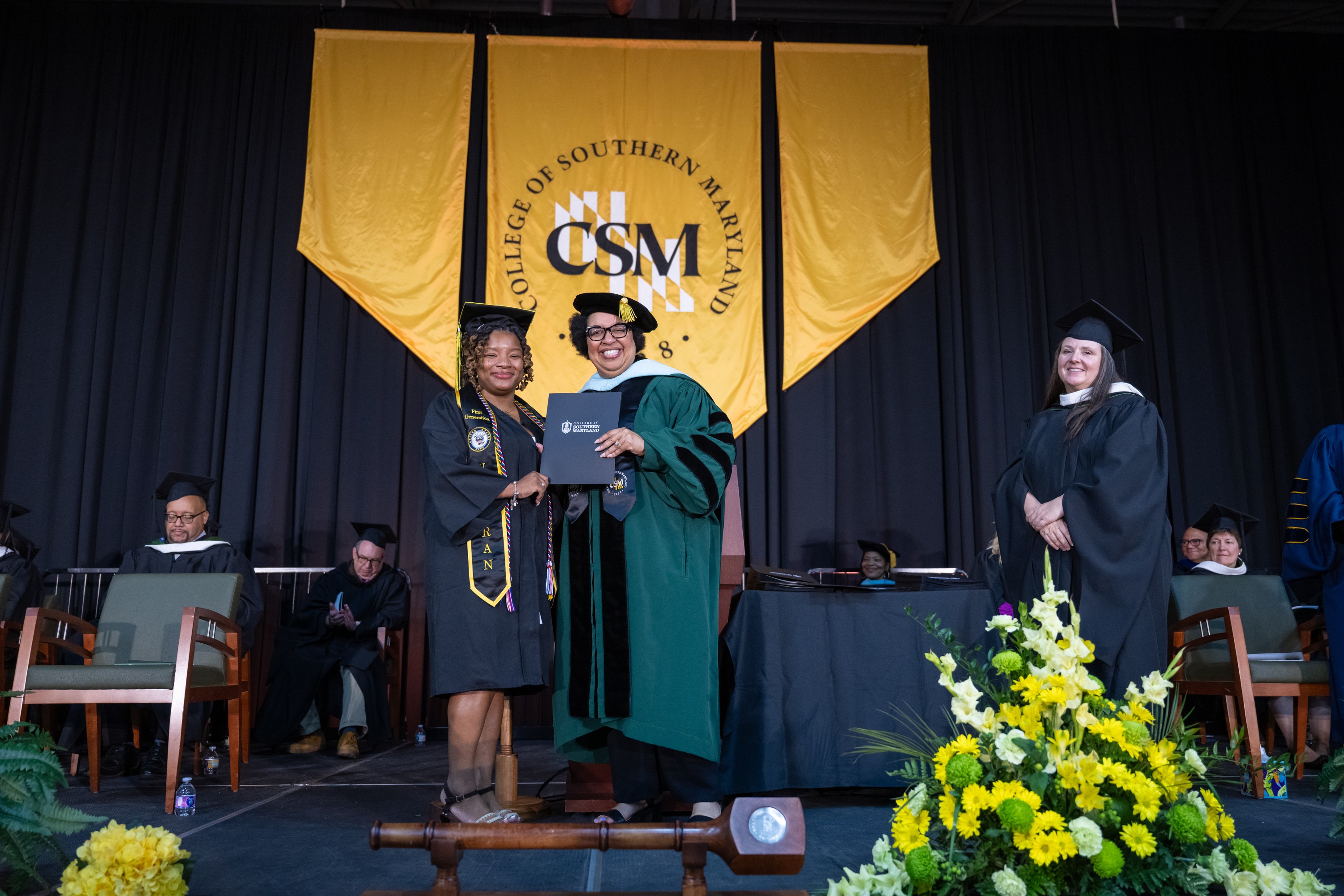 Ria Robinson poses with CSM President on stage during graduation