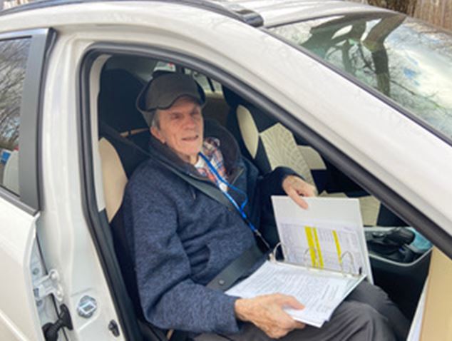 elderly man sits in a car